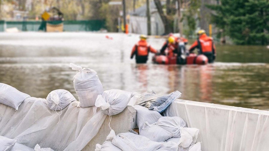 Vreče s peskom s poplavljenimi hišami in reševalno ekipo v ozadju