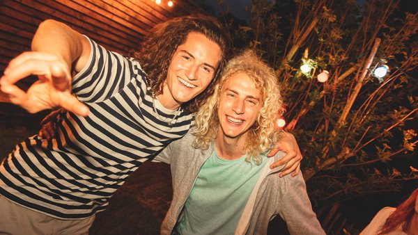 Zakaj je na festivalih pomembno biti zavarovan? Dva mlada moška, ki se smejita v kamero