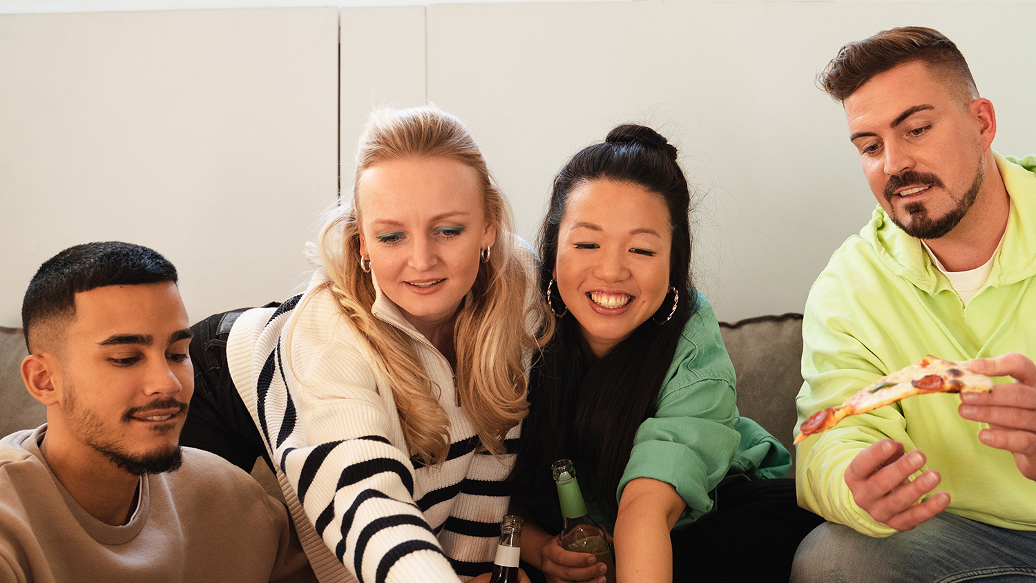 Štirje mladi sedijo skupaj na kavču in se smejijo 