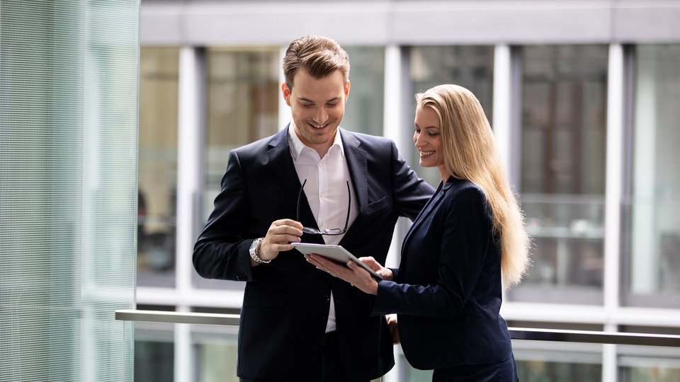 Poslovni moški in ženska v profesionalnih oblačilih skupaj gledata tablico